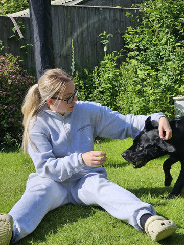 A woman spending time with a black dog in a garden.